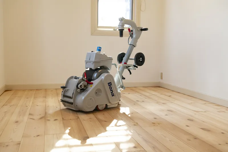 日当たりのよい部屋で、木の床を削るフローリングサンダー